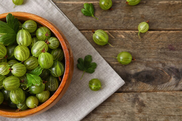 Bowl with fresh ripe gooseberry on wooden background