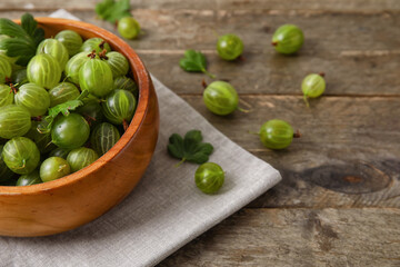 Bowl with fresh ripe gooseberry on wooden background