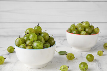 Bowls with fresh ripe gooseberry on table