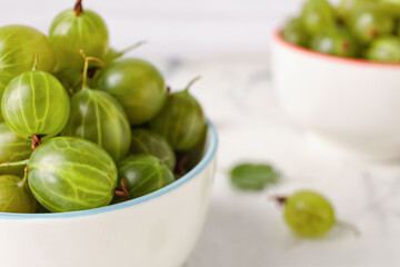Bowls with fresh ripe gooseberry on table