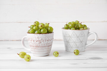 Cups with fresh ripe gooseberry on table