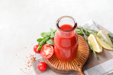 Bottle of tasty tomato juice on light background