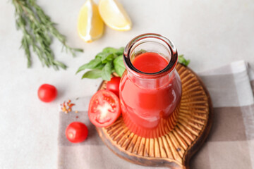 Bottle of tasty tomato juice on light background