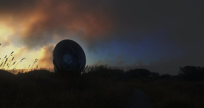Mystical sunset sky with dark clouds shadowing a parabolic reflector - pan view