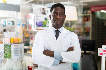 Portrait of an african american male pharmacist standing in the sales hall of a pharmacy. Close-up portrait