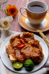 Batagor, Indonesian traditional and street food. Batagor made by fried fish dumpling with fried tofu and served in peanut sauce and served with a cup of tea and lime