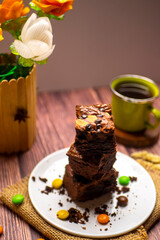 pile of chocolate brownies with a green cup of tea photographed on wood textured table