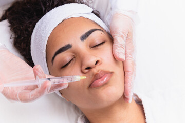 Lip augmentation. Beautiful Young Woman's Mouth Receiving Hyaluronic Acid Injection. Closeup Of...
