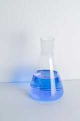 Laboratory glass Erlenmeyer conical flask filled with blue chemical liquid for a chemistry experiment in a science research lab,COPY SPACE