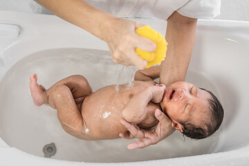 little newborn infant baby having bathing by mother with baby bathtub