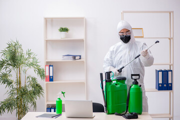 Young male contractor disinfecting office during pandemic