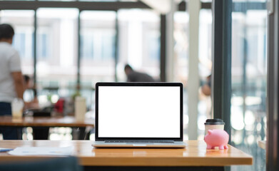Laptop with blank screen on working desk , financial money saving with pink piggy bank.