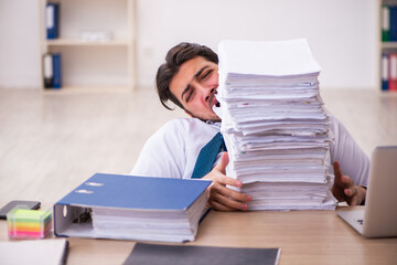 Young businessman employee unhappy with excessive work in the office