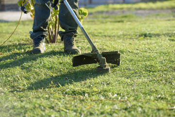 A man mows the grass on the front lawn with a mower