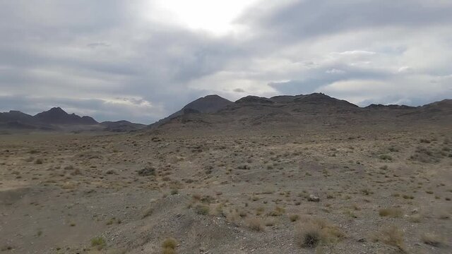 Gloomy prairie landscape in Western Utah. In background gray clouds and barren mountains. Panning shot
