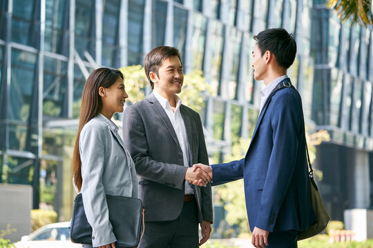 asian business associates shaking hands outdoors