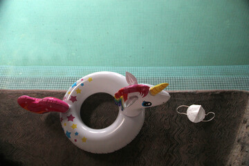 Pool to play on vacation next to flip-flops and an inflatable unicorn with face masks for the new...