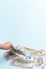 Child's hand holding one hundred dollar bill, vertical frame, copy space. Cost of raising a child