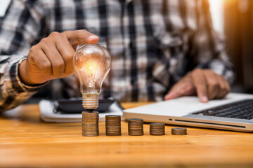 Business man holding light bulb on the Green background nature and writing on note book it for financial