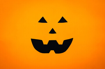 Halloween pumpkin face background from cutting orange and black paper. Minimal halloween concept.