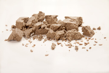 Pieces of sunflower halva are scattered on a white background.