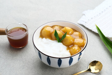 Bubur candil or kolak biji salak, Indonesian traditional food made from sticky rice flour, brown sugar and coconut milk. Popular during ramadan. Served in white bowl on grey background. Close up.
