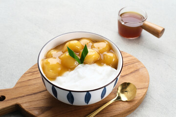 Bubur candil or kolak biji salak, Indonesian traditional food made from sticky rice flour, brown sugar and coconut milk. Popular during ramadan. Served in white bowl on grey background. Close up.
