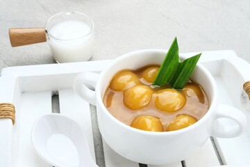 Bubur candil or kolak biji salak, Indonesian traditional food made from sticky rice flour, brown sugar and coconut milk. Popular during ramadan. Served in white bowl on grey background. Close up.
