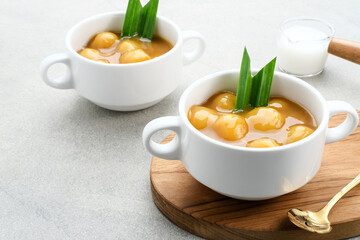 Bubur candil or kolak biji salak, Indonesian traditional food made from sticky rice flour, brown sugar and coconut milk. Popular during ramadan. Served in white bowl on grey background. Close up.
