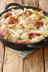American Chicken bog is a pilaf style dish made of rice, chicken, onion, spices, and sausage closeup in the pan on the table. Vertical