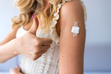 Successful Inoculation Against Coronavirus. Smiling Vaccinated Woman Gesturing Thumbs Up Showing Shoulder With Patch After Covid-19 Vaccine Injection Sitting On Chair. Recommended inoculation