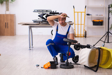Young male repairer repairing perambulator indoors