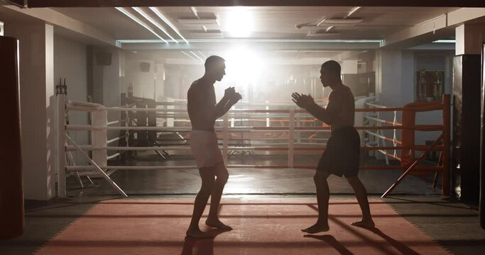 Kickboxing, man boxers train in sparring, they performs strikes with their feet, training day in the boxing gym.
