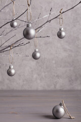 Merry Christmas! Christmas concept, minimalism. Branches of trees with Christmas tree decorations on a gray background of a silver color.