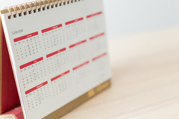 Calendar page close up on wood table with white wall background business planning appointment meeting concept