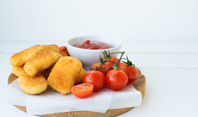Homemade chicken nuggets with sauce and tomatoes on a wooden board, copy space