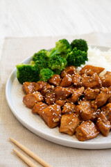Homemade Teriyaki Chicken with Rice and Broccoli on a plate on a white wooden background, side view.