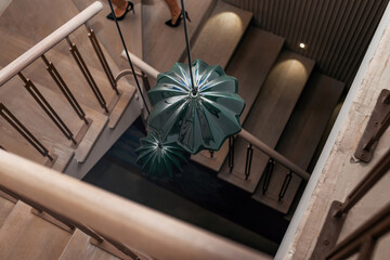 Focus on the chandelier above the spiral staircase. Top view. Unrecognizable girl with beautiful legs climbs the stairs
