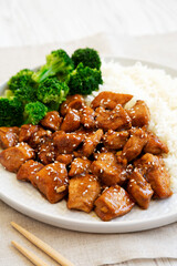Homemade Teriyaki Chicken with Rice and Broccoli on a plate on a white wooden surface, side view. Close-up.