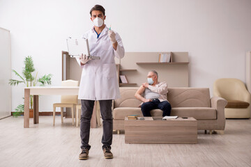Young male doctor visiting old patient in vaccination concept