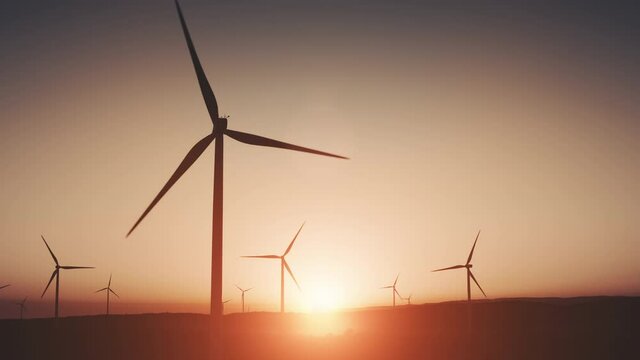 Wind generators on land. Red Sky. Sunset soft light. Green energy. Clean natural source power. Turbines are turning. Purple clear morning sky. Summer background. Nature environment