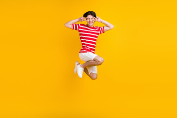 Fototapeta na wymiar Full size photo of happy positive young make v-signs jump up good mood summer isolated on yellow color background