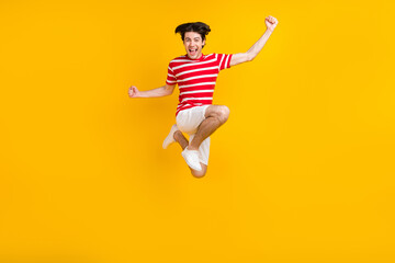 Fototapeta na wymiar Full size photo of happy cheerful young raise fists jump up good mood winner isolated on yellow color background