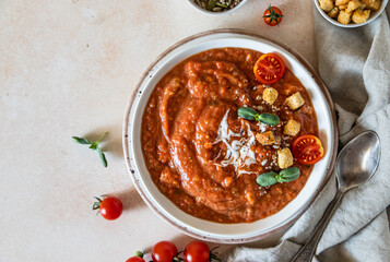 Vegetable soup with baked tomato, bell pepper, cream, breadcrumbs and micro greens in white bowl on light concrete background. Top view.