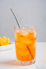 Drinking glass full of orange cold fresh juicy drink served with ice cubes, metal straw and sliced...