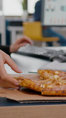 Closeup of businesswoman having fast food order takeout lunchtime working in startup company office. Executive manage taking slice of pizza. Lunch meal break package delivered at startup office.