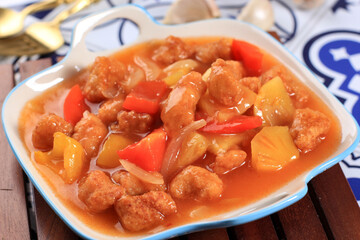 Ayam Kuluyuk or Ayam Goreng Saus Asam Manis, Fried Chicken with Sweet Sour Sauce, Chinese Indonesian Culinary Food Served on White Rim Blue Plate.