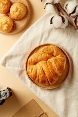 Quick breakfast to start the day. Croissant, toasted coconut cake in plate, coffee on beige pastel background. Top view, flatlay. Soft Light