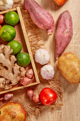 Prepare ingredients for healthy and nutritious meals.  Potato, Purple sweet potato, dry onion, red pumpkin, ginger on brighten wooden background. Top view. Clean and Fresh Food. Healthy vegetables.