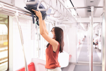 Asian traveler woman putting her luggage on overhead shelf in train